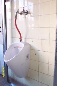 Manuelle Betätigung des Urinalspülers durch einen Gartenwasserhahn gesehen in München.